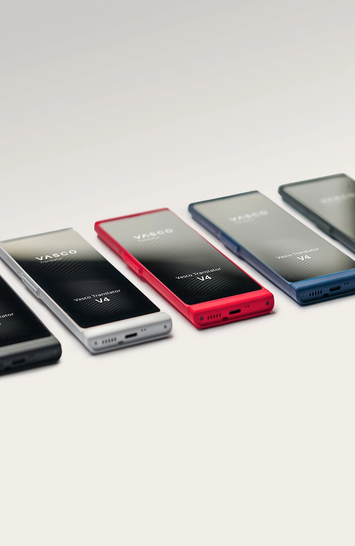 Vijf vertaalapparaten liggen naast elkaar in de kleuren zwart, wit, rood, blauw en grijs.