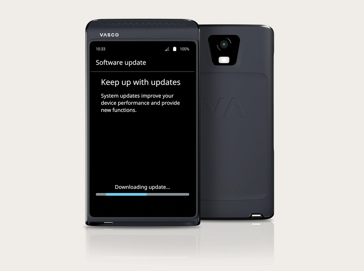 Een studiofoto van de Vasco Translator Q1 waarop het proces van de software-update te zien is. Er zijn twee apparaten te zien: één van voren en één van achteren. Op het apparaat aan de voorkant is een scherm met de tekst „Software-update“ te zien, met het bericht „Blijf op de hoogte van updates“ en een blauwe voortgangsbalk die aangeeft dat „De update wordt gedownload...“. Op de achterkant van het apparaat vallen de cameralens en het in reliëf aangebrachte „VA“-logo op.