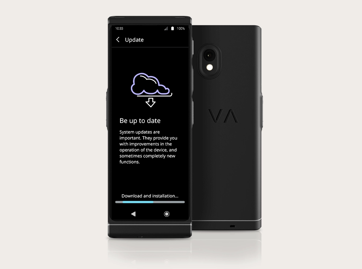 Een studiofoto van de Vasco Translator V4 waarop de interface voor systeemupdates te zien is. Twee zwarte apparaten staan naast elkaar: één met de voorkant naar voren en één met de achterkant naar voren. Op het scherm is een wolkpictogram met een downloadpijl te zien, de kop „Blijf up-to-date“ en onderaan een voortgangsbalk met het opschrift „Downloaden en installeren...“. Op de achterkant zijn de camera met dubbele lens en het „VA“-logo in reliëf te zien.